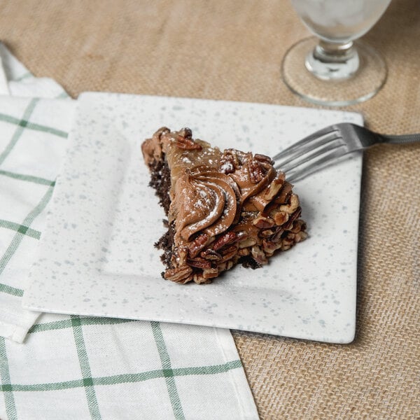 A piece of cake on a 10 Strawberry Street blue speckled porcelain dinner plate with a fork.