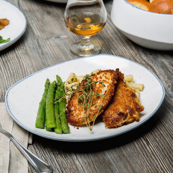 A rectangular porcelain dinner plate with chicken and asparagus on a table.