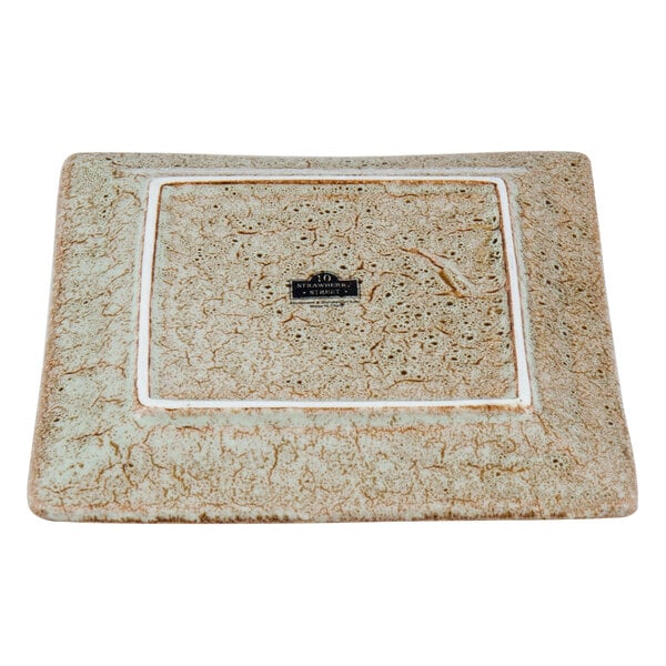 A close-up of a 10 Strawberry Street square porcelain bread and butter plate with a white border and a brown and white tiger eye design.