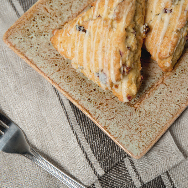 A 10 Strawberry Street Tiger Eye porcelain bread and butter plate with scones and a fork on a table.