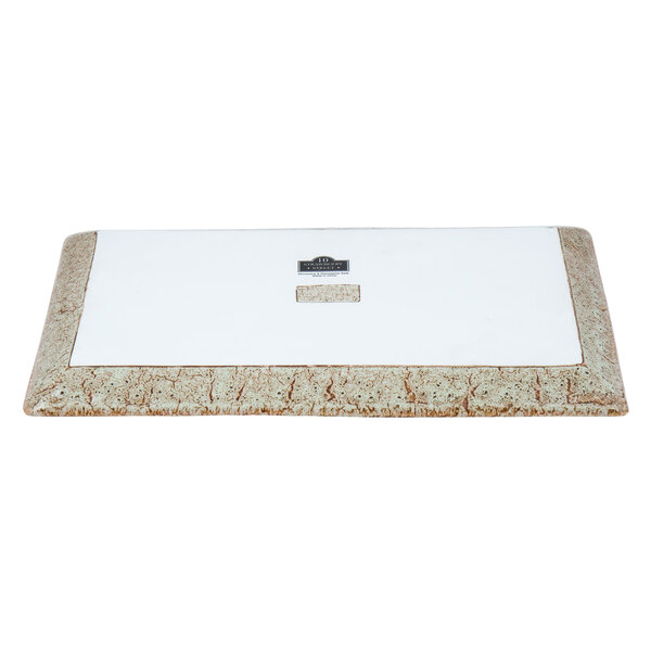 A white rectangular porcelain platter with brown and black rectangles on the top.