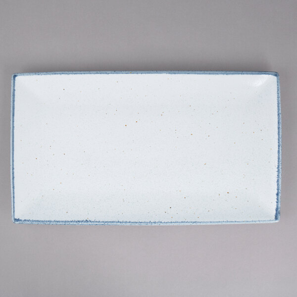 A white rectangular porcelain platter with blue specks on the surface.