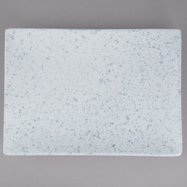 A white rectangular porcelain platter with blue specks on the surface.