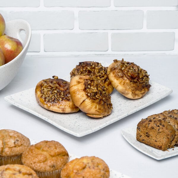 A rectangular blue speckled porcelain platter holding a variety of pastries and muffins.