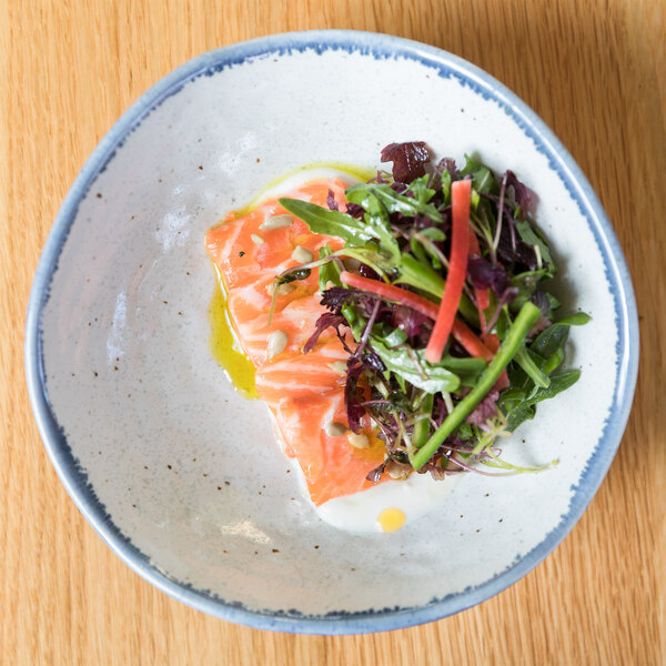 A 10 Strawberry Street Arctic Blue bowl filled with a vegetable salad on a table.