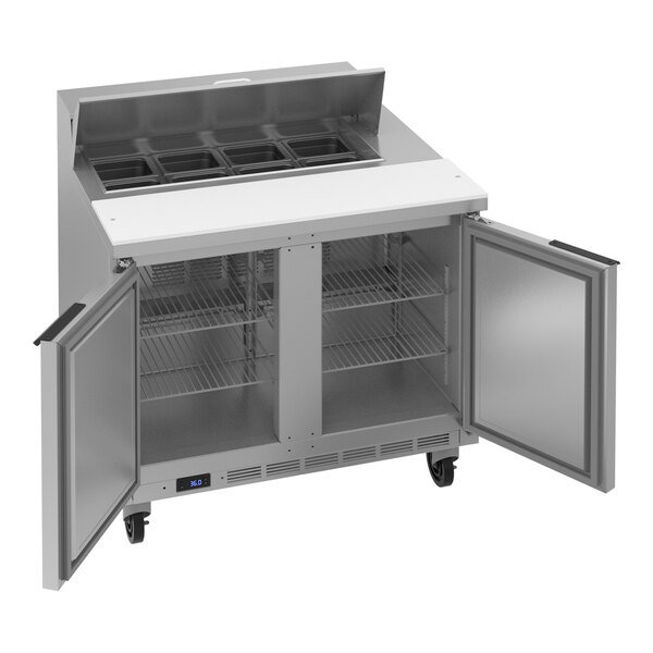 A stainless steel refrigerated sandwich prep table with two open doors, interior shelves, and ingredient bins on top.