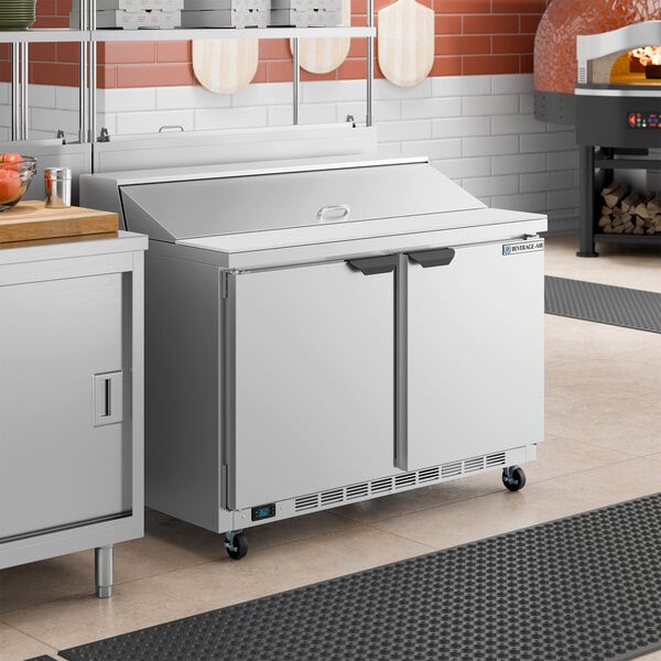 A stainless steel, two-door ADA height refrigerated sandwich prep table with a raised ingredient rail and a flat work surface.