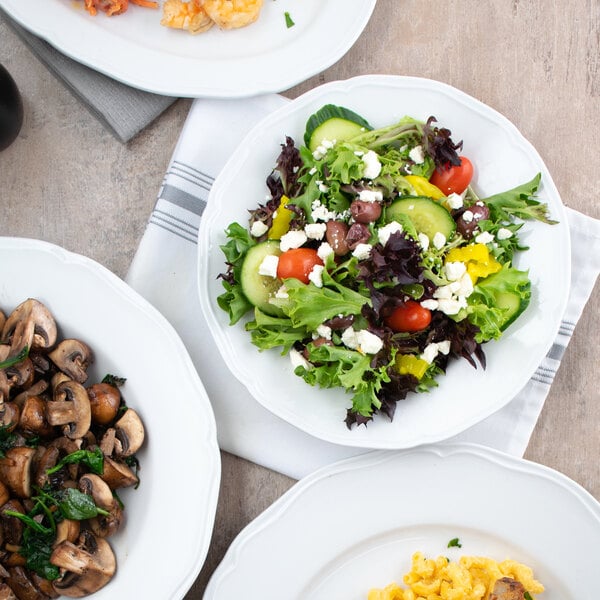 A group of Tuxton Charleston bright white china bowls filled with salad, mushrooms, and eggs on a table.
