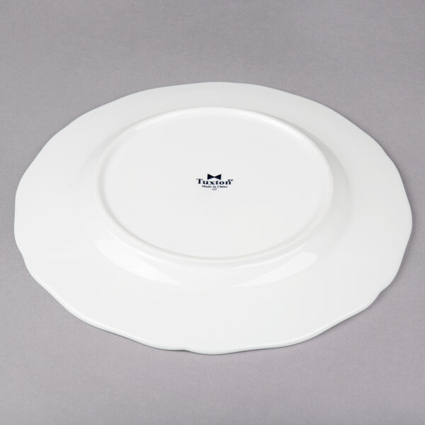 A Tuxton TuxTrendz Charleston white china plate with a scalloped edge and black rim.