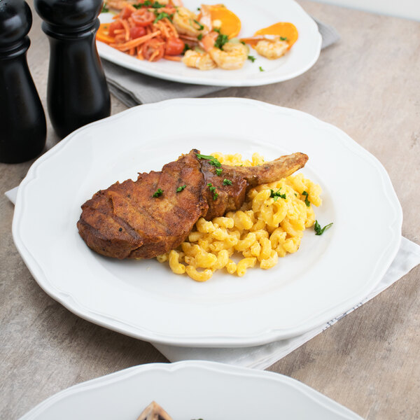 A Tuxton Charleston scalloped china plate with food on a table.