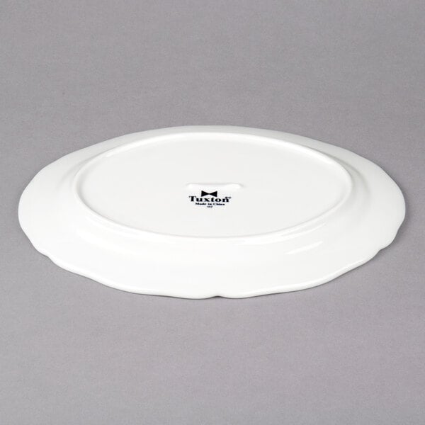 A white Tuxton china oval platter with a scalloped edge.