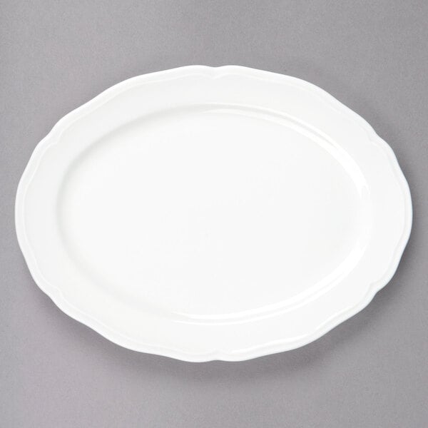 A Tuxton TuxTrendz white china oval platter with a scalloped edge.