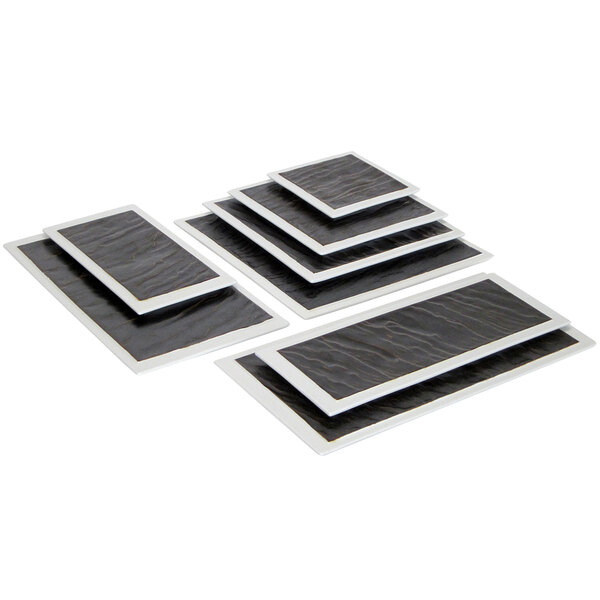 A stack of black and white square Tuxton China plates.