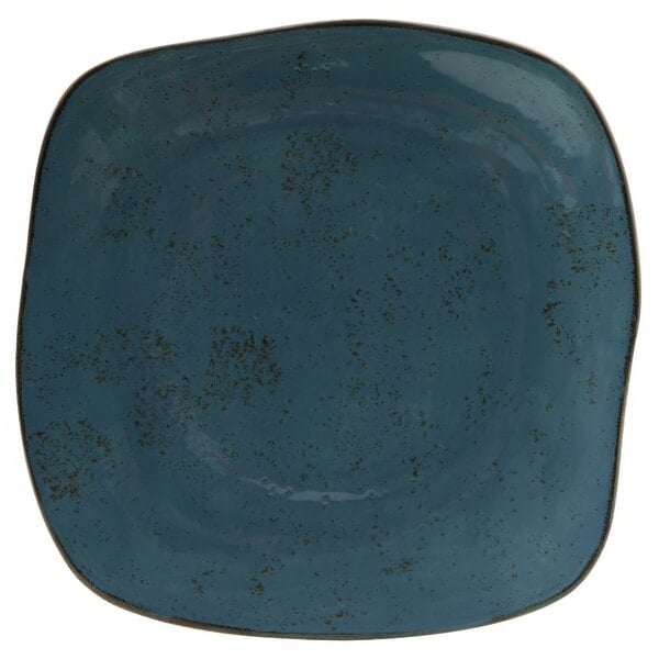 A white square Tuxton china plate with a blue surface and specks.