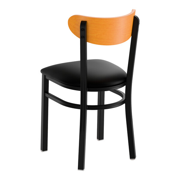 A black metal chair with a black vinyl seat and a curved cherry wood backrest.