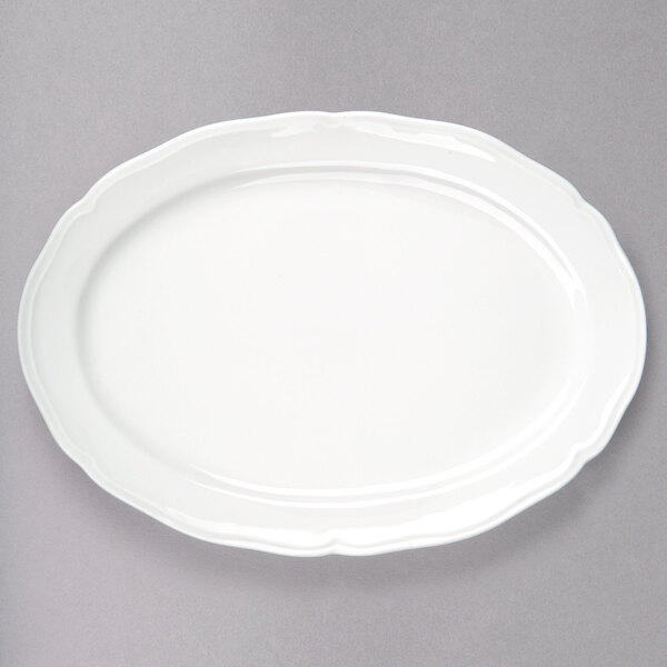 A white Tuxton oval platter with a scalloped edge.