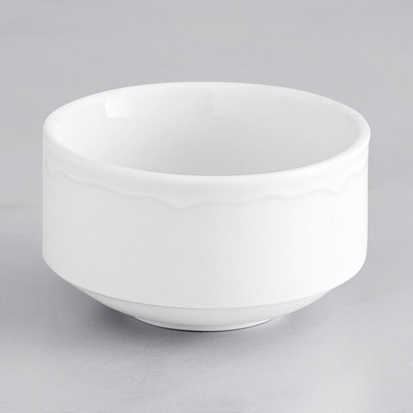 A Tuxton Charleston bright white scalloped edge bowl on a gray surface.