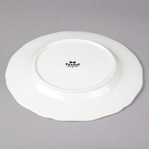 A Tuxton TuxTrendz white china plate with a scalloped edge.