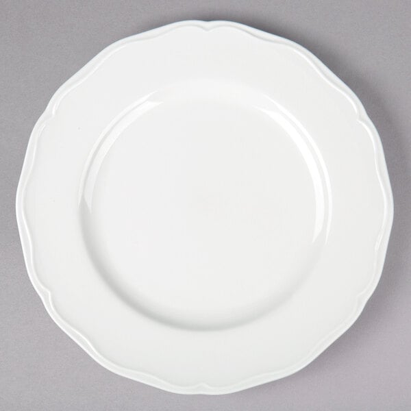 A Tuxton TuxTrendz Charleston white china plate with a scalloped edge.