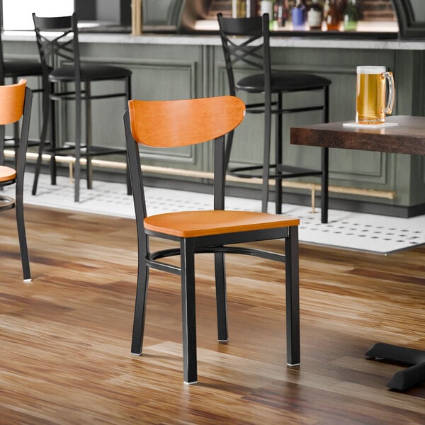 A black metal chair with a cherry wood seat and backrest.