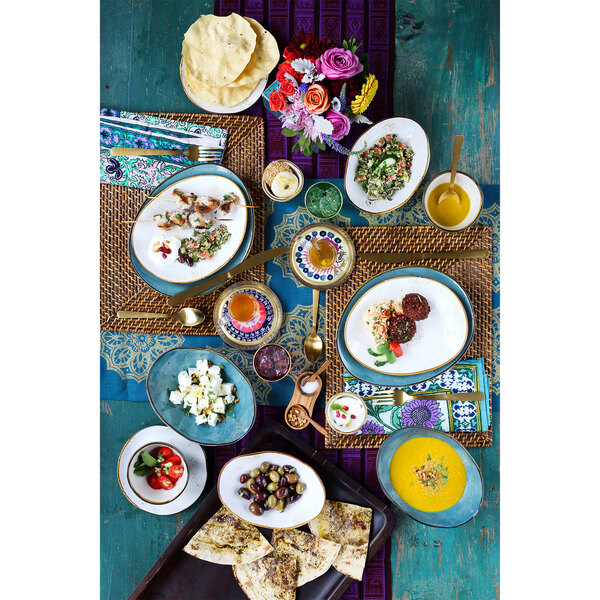 A table with Tuxton TuxTrendz Artisan Geode Agave square plates of food and flowers.