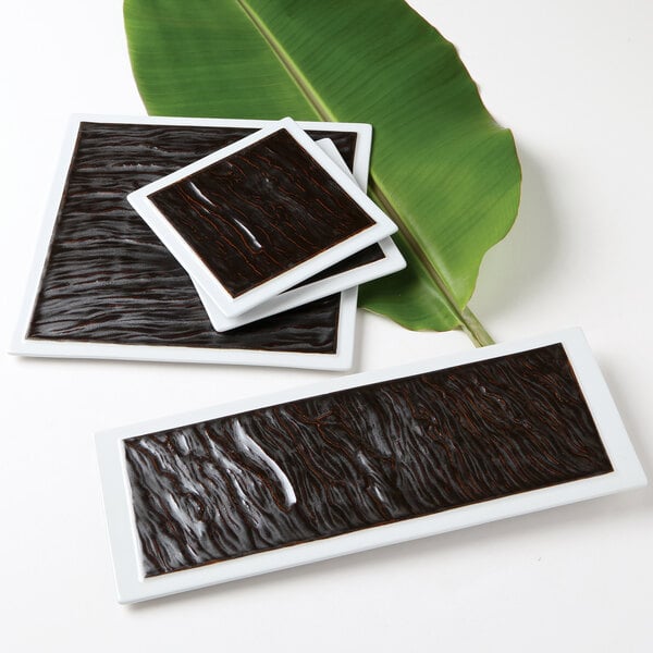 A stack of rectangular white plates with a black surface.