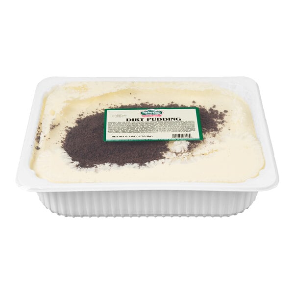 A rectangular white container filled with creamy pudding topped with a patch of crumbled chocolate cookie crumbs and a label on top.