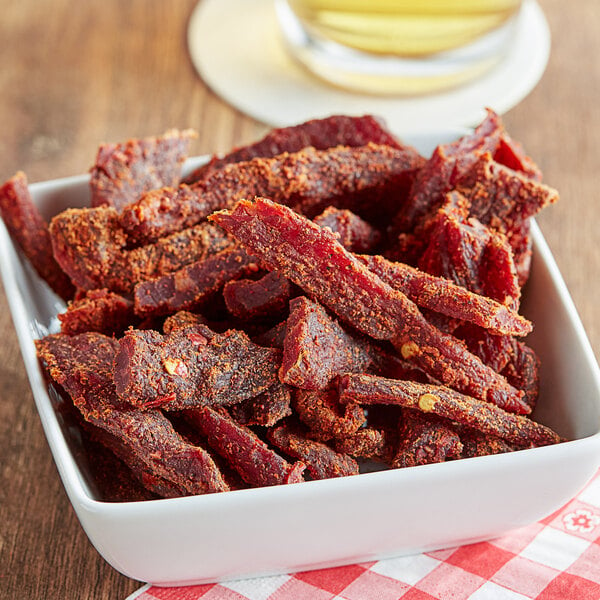 A bowl of Uncle Mike's Spicy Hot Beef Jerky on a table.