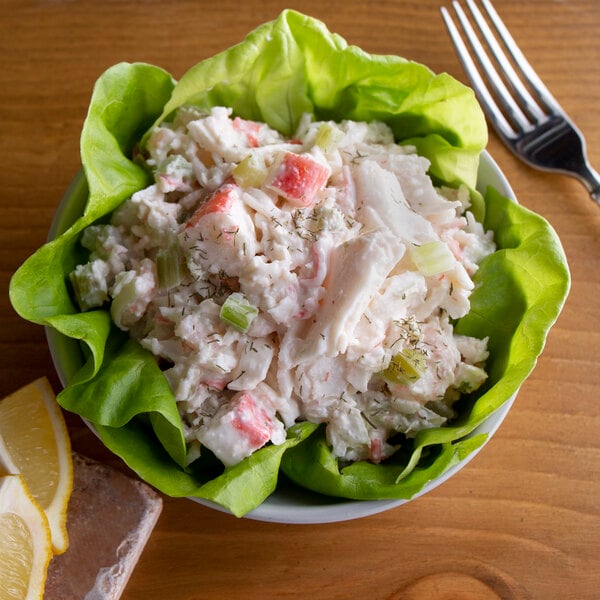 A bowl of Spring Glen Fresh Foods Seafood Salad with a fork and lemon.