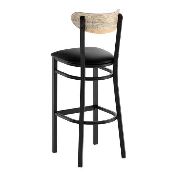 A black metal bar stool with a black vinyl seat and a curved driftwood backrest.