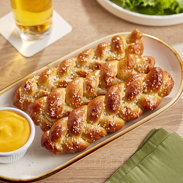 A bakery display with a plate of Dutch Country Foods Pennsylvania Dutch Soft Pretzel Braid with a glass of beer on the side.