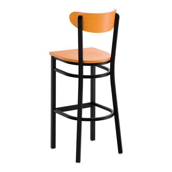 A bar stool with a black metal frame and cherry wood seat and back.
