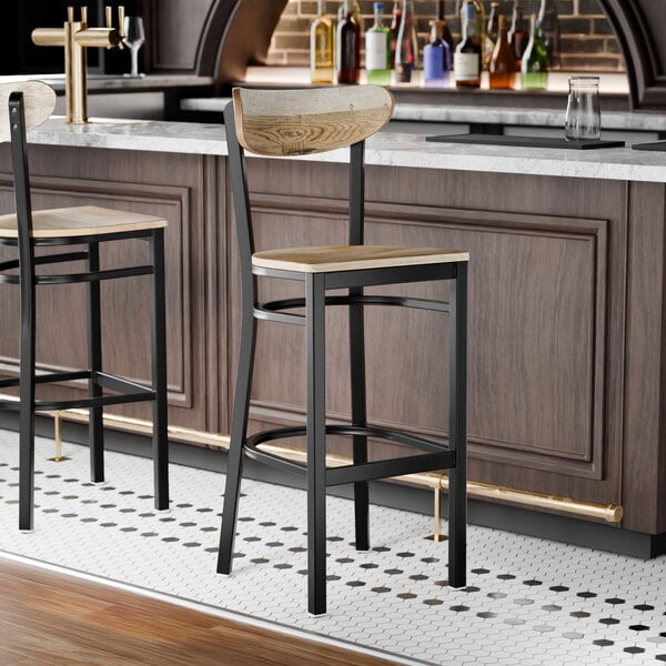 A black metal bar stool with a driftwood-finished wooden seat and backrest.