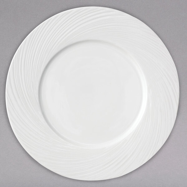 A white Arcoroc porcelain service plate with a circular wavy design.