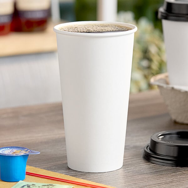 A white Choice paper hot cup on a table with brown liquid in it.