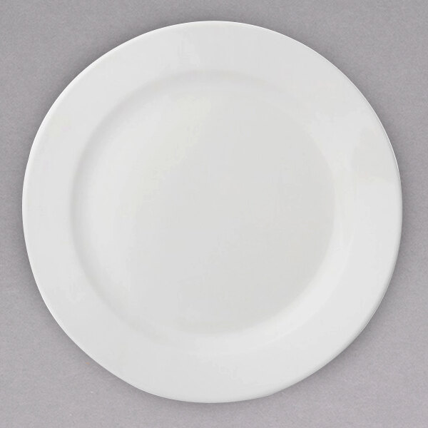 An Arcoroc white porcelain salad plate with a white rim on a gray surface.