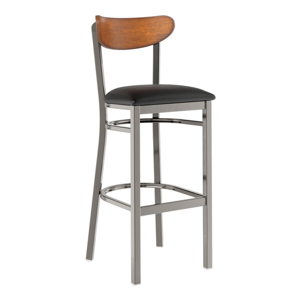 A Lancaster Table & Seating bar stool with a black vinyl seat and wood back on a metal frame.