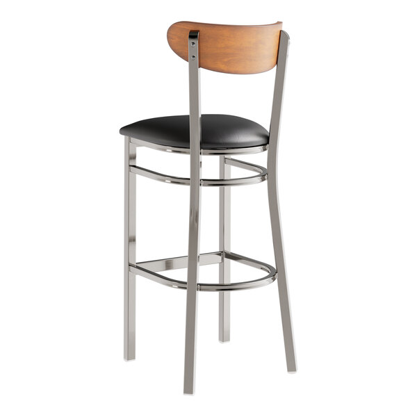 A Lancaster Table & Seating bar stool with a black vinyl seat and chrome legs.