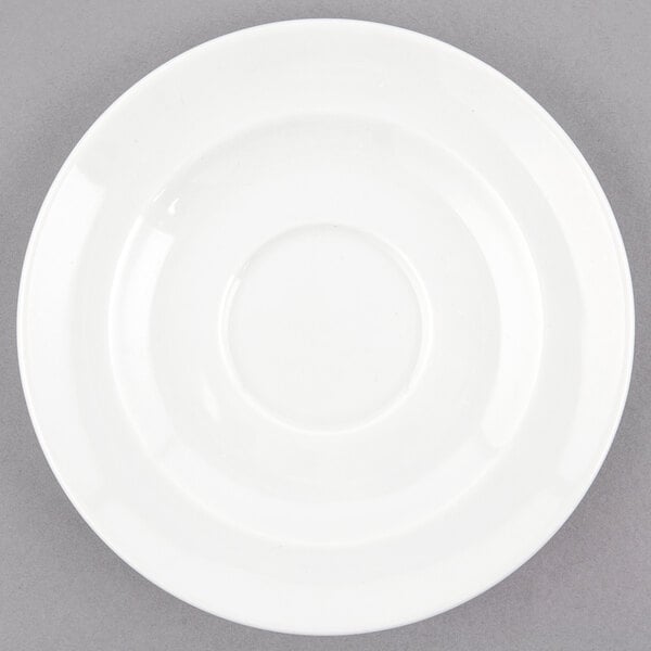 A white porcelain saucer with a small rim on a gray surface.