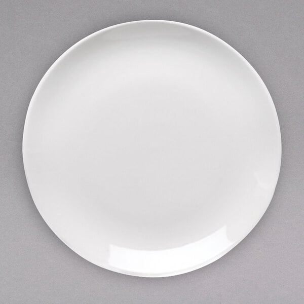 An Arcoroc white porcelain coupe plate on a gray surface.