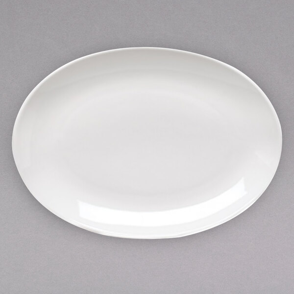 A white oval Arcoroc porcelain platter with a white rim on a gray surface.
