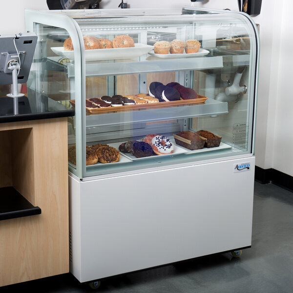 An Avantco glass shelf in a bakery display case with pastries on it.