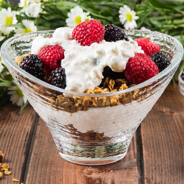 An Arcoroc glass bowl of food with berries and yogurt.