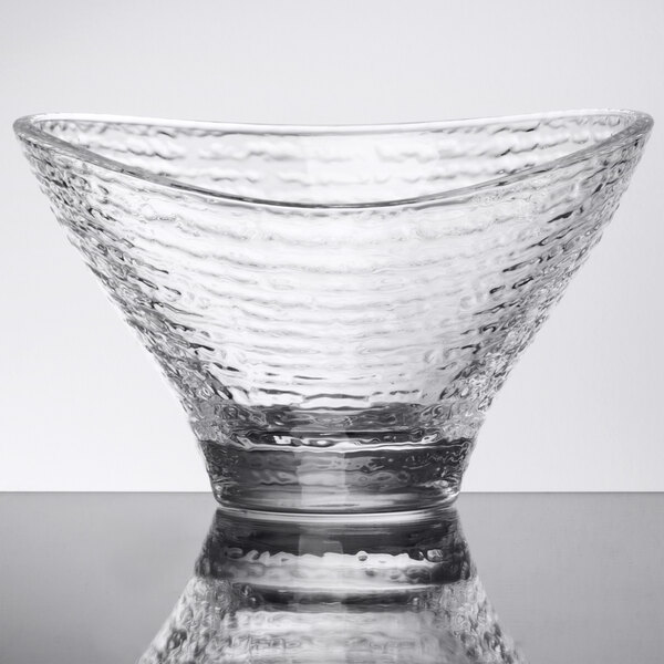 An Arcoroc clear glass bowl with a curved rim on a white surface.