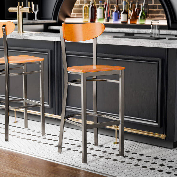 A bar stool with a cherry wood seat and back, and a metal frame with a clear coat finish.