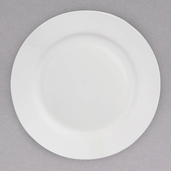 A close-up of an Arcoroc white porcelain banquet plate on a gray surface.