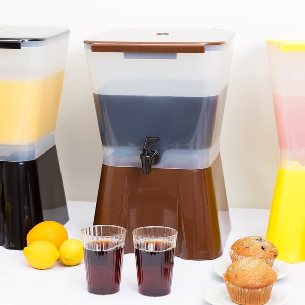 A Tablecraft brown plastic beverage dispenser next to a variety of drinks and fruit.