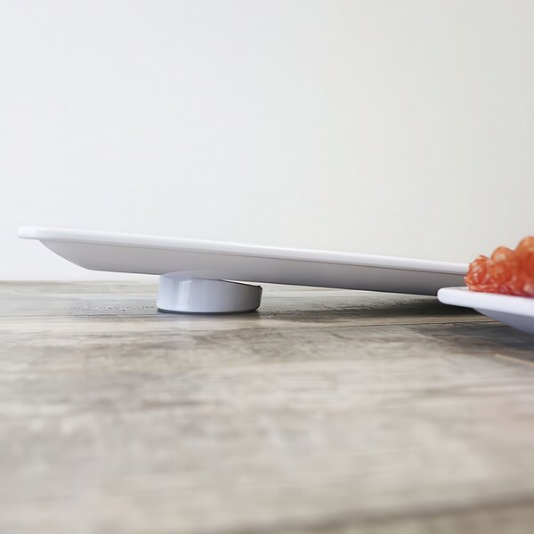A white Elite Global Solutions round melamine riser with food on a plate on top of it.