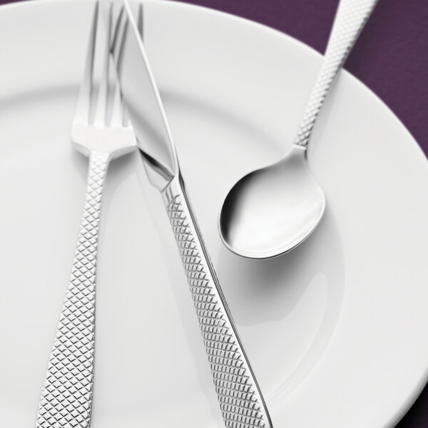 A white plate with a Oneida Jade stainless steel serving spoon on it.