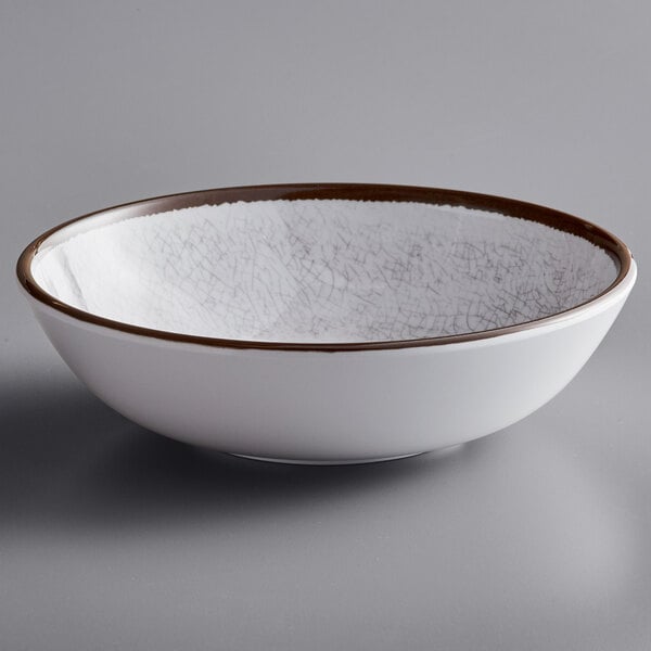 A white Elite Global Solutions melamine bowl with a brown rim.
